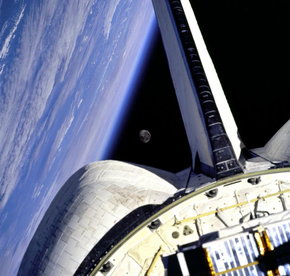 Earth and its Moon are nicely framed in this image taken from the aft windows of the Space Shuttle Discovery in 1998. Discovery - on mission STS-95 - was flying over the Atlantic Ocean at the time this image was taken. 