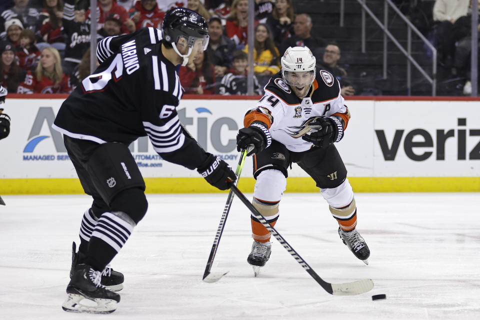 Anaheim Ducks center Adam Henrique (14) reaches for the puck as New Jersey Devils defenseman John Marino (6) clears it during the first period of an NHL hockey game Sunday, Dec. 17, 2023, in Newark, N.J. (AP Photo/Adam Hunger)