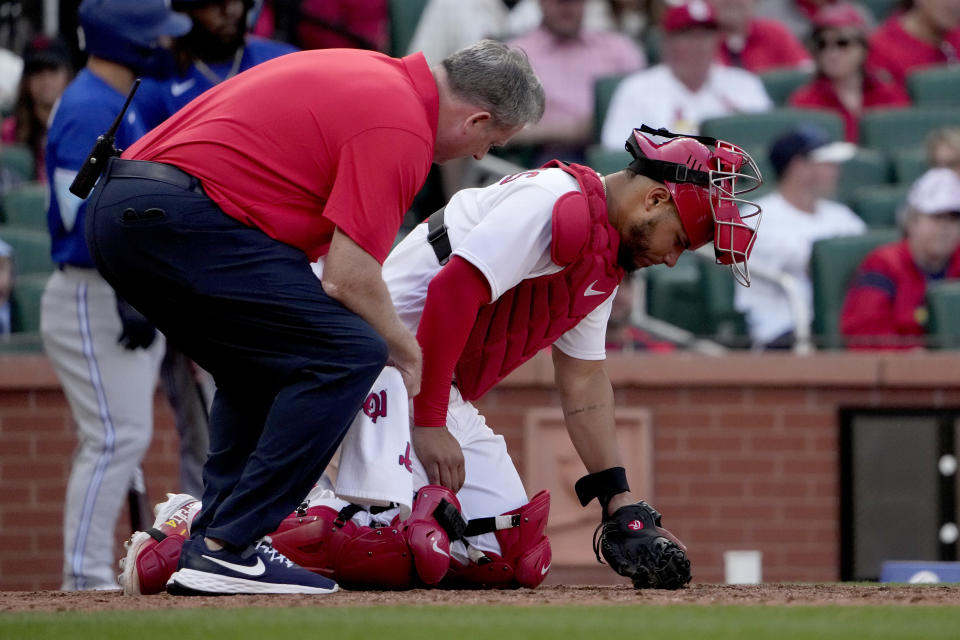 St. Louis Cardinals catcher Willson Contreras is checked on by trainer Chris Conroy after being injured during the eighth inning of an opening day baseball game against the Toronto Blue Jays Thursday, March 30, 2023, in St. Louis. Contreras left the game. (AP Photo/Jeff Roberson)