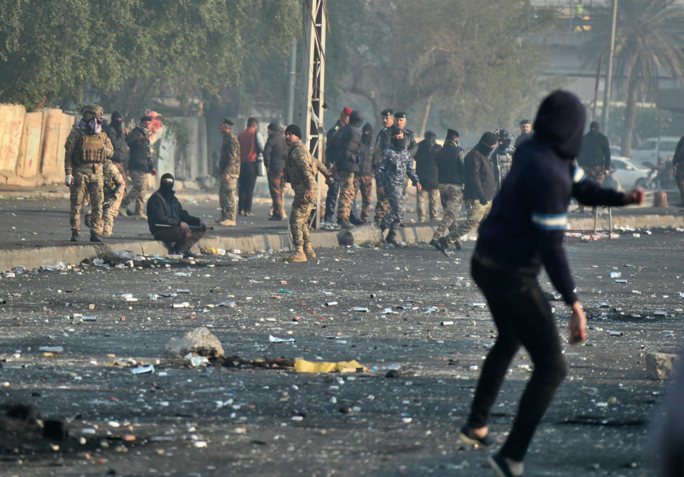 An anti-government protester throws a stone towards security forces during an ongoing protest in central Baghdad, Iraq, Monday, Jan. 20, 2020. (AP Photo/Hadi Mizban)