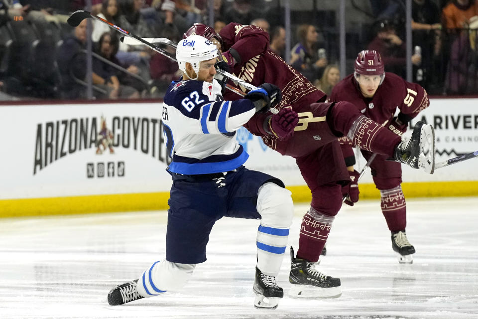 Winnipeg Jets right wing Nino Niederreiter (62) flips Arizona Coyotes center Liam O'Brien on the ice as Coyotes defenseman Troy Stecher (51) looks on during the first period of an NHL hockey game Saturday, Nov. 4, 2023, in Tempe, Ariz. (AP Photo/Ross D. Franklin)