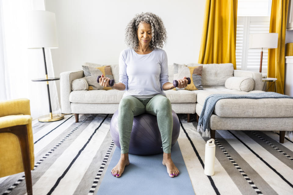 Senior woman lifting weights in living room