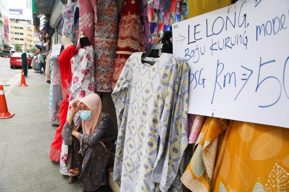 A clothing vendor waits for customers in front of her stall at Jalan Masjid India on the eve of Hari Raya Aidilfitri May 12, 2021. — Picture by Choo Choy May