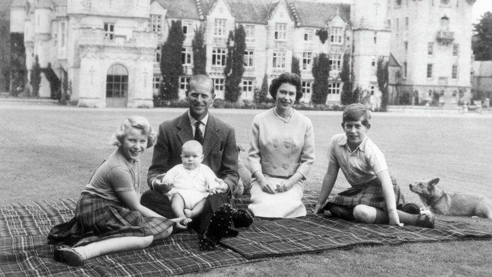 Baby Prince Andrew perches on Prince Philip's lap during a picnic on the grounds of Balmoral Castle. Also pictured are Queen Elizabeth, Prince Charles, and Princess Anne.