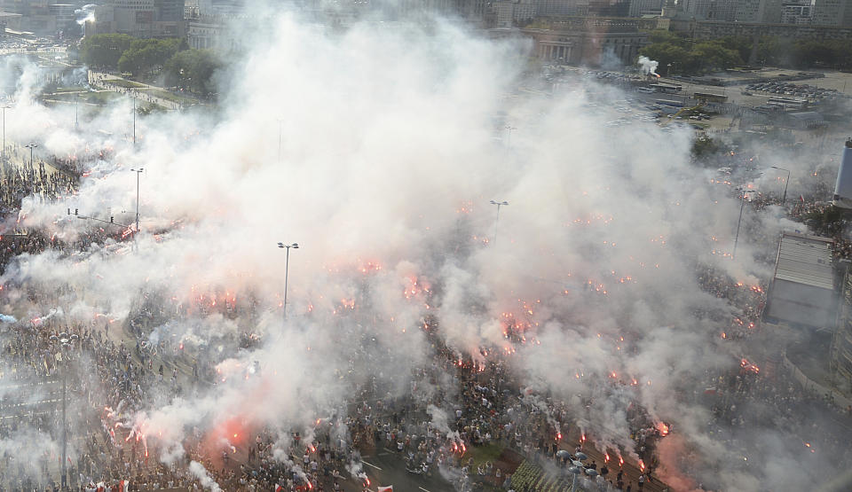 Warsaw residents stand with national flags and flares to observe a minute of silence for the fighters and victims of the 1944 Warsaw Rising against the Nazi German occupiers, on the 74th anniversary of the revolt, in downtown Warsaw, Poland, Wednesday, Aug. 1, 2018. (AP Photo/Czarek Sokolowski)