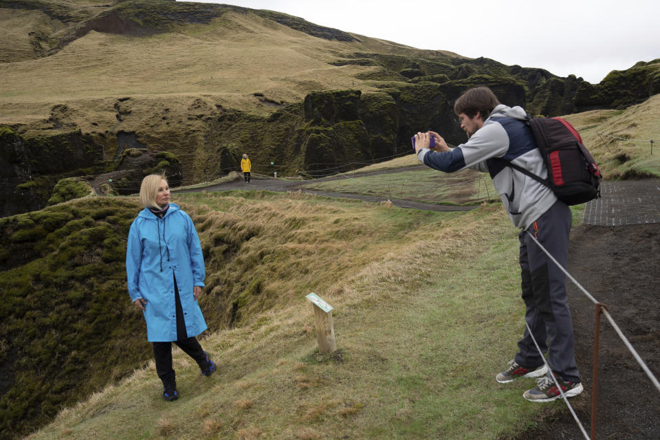 In this photo taken Wednesday, May 1, 2019, Russian tourist Nadia Kazachenok poses for a photograph taken by Mikhail Samarin at the Fjadrárgljúfur. The canyon is closed, with roadblocks and rope fences, but tourists were quick to pass when the ranger went off duty on a Wednesday afternoon. (AP Photo/Egill Bjarnason)