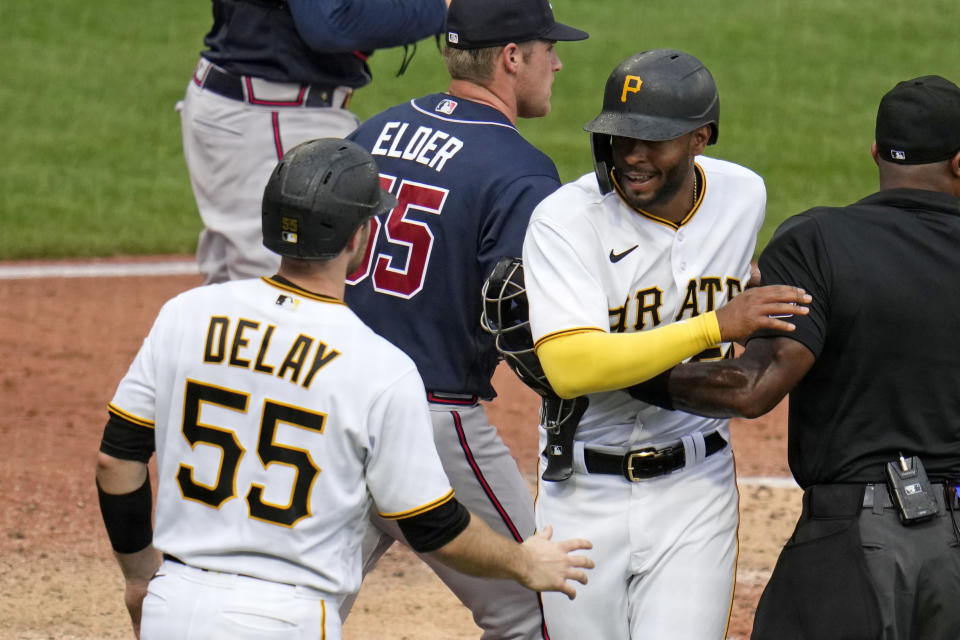 Pittsburgh Pirates' Josh Palacios, second from right, is greeted by Jason Delay (55), as he runs into umpire Alan Porter, right, after scoring the second run on a single by Ke'Bryan Hayes off Atlanta Braves starting pitcher Bryce Elder, center, during the third inning of a baseball game in Pittsburgh, Thursday, Aug. 10, 2023. (AP Photo/Gene J. Puskar)