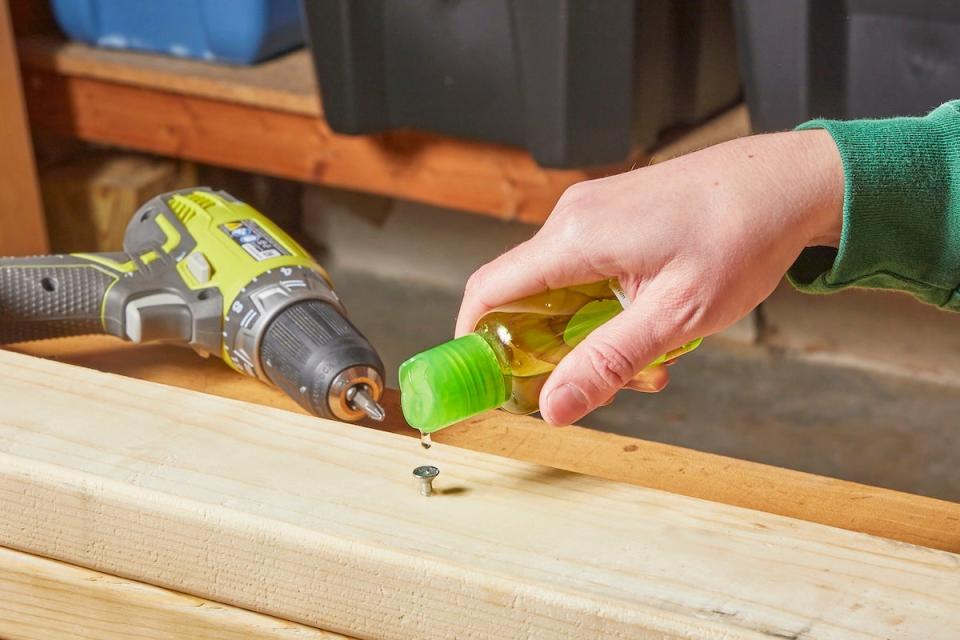 A person pouring a drop of liquid abrasive onto the head of a stripped screw.