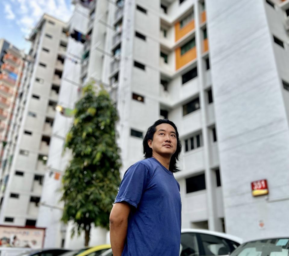 Zachary Loo looking contemplative with an HDB block in the background, illustrating a story on singles and HDB BTO.