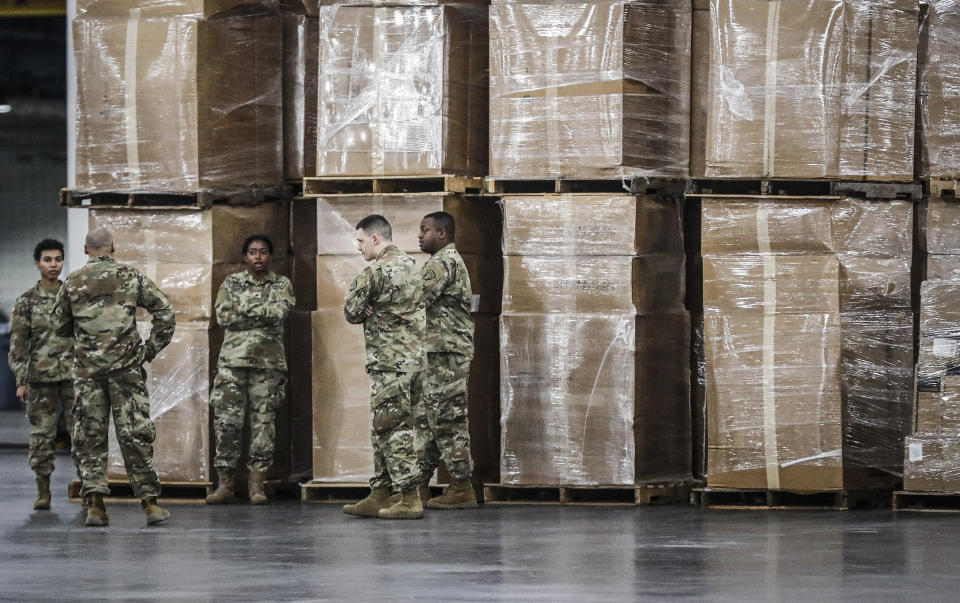 FILE - U.S. National Guard members stand beside crates of medical equipment at the Jacob Javits Center on March 23, 2020, in New York. Gov. Kathy Hochul is sending 50 more New York National Guard members to bolster members out at nursing homes and long-term care facilities. (AP Photo/John Minchillo, File)