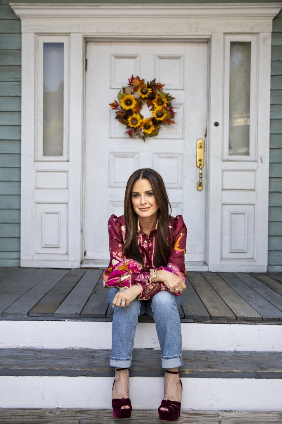 An actor sits on the steps of a house on the Universal Studios backlot