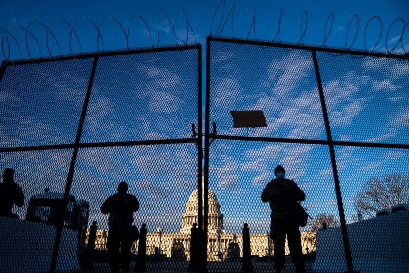 WASHINGTON, DC - JANUARY 16: National Guard troops stand behind security fencing with the dome of the U.S. Capitol Building behind them, on Saturday, Jan. 16, 2021 in Washington, DC. After last week's riots and security breach at the U.S. Capitol Building, the FBI has warned of additional threats in the nation's capital and across all 50 states. (Kent Nishimura / Los Angeles Times)