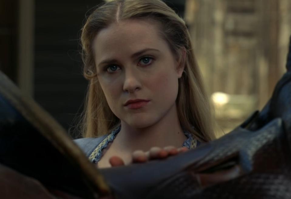 Evan Rachel Wood as Dolores looking over the saddle of a horse at something