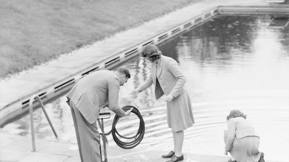 King George VI, Princess Elizabeth and Princess Margaret collect water from a swimming pool at the Royal Lodge