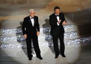 <p>The Father Of The Bride actor has hosted the actors solo twice before, but in 2010 returned with Alec Baldwin. </p><p>The actors arrived to deliver their monologue from the ceiling (with Cabaret feather dancers either side of them) where they gave some old-school Hollywood simple jokes: 'Oh there's that damn Helen Mirren...' 'Oh no, that's Dame Helen Mirren.'</p>
