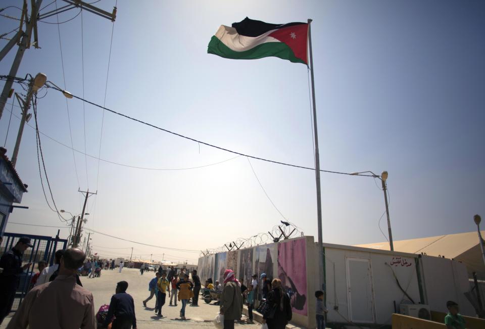 In this Thursday April 17, 2014 photo, the Jordanian flag waves over the main entrance to Zaatari refugee camp near the Syrian border in Jordan. Some residents, frustrated with Zaatari, the region's largest camp for Syrian refugees, set up new, informal camps on open lands, to escape tensions and get closer to possible job opportunities.(AP Photo/Khalil Hamra)