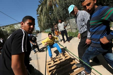 Palestinian Mohammad Baraka, 20, nicknamed by people as Gaza Samson, pulls a fuel tanker by a rope attached to his teeth as he exercises in Deir al-Balah in the central Gaza Strip March 5, 2016. REUTERS/Mohammed Salem