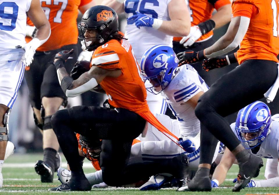 BYU's Max Tooley (31) pulls the shirt of Oklahoma State's Ollie Gordon II (0) in the second half of the college football game between the Oklahoma State University Cowboys and the Brigham Young Cougars at Boone Pickens Stadium in Stillwater, Okla., Saturday, Nov. 25, 2023.