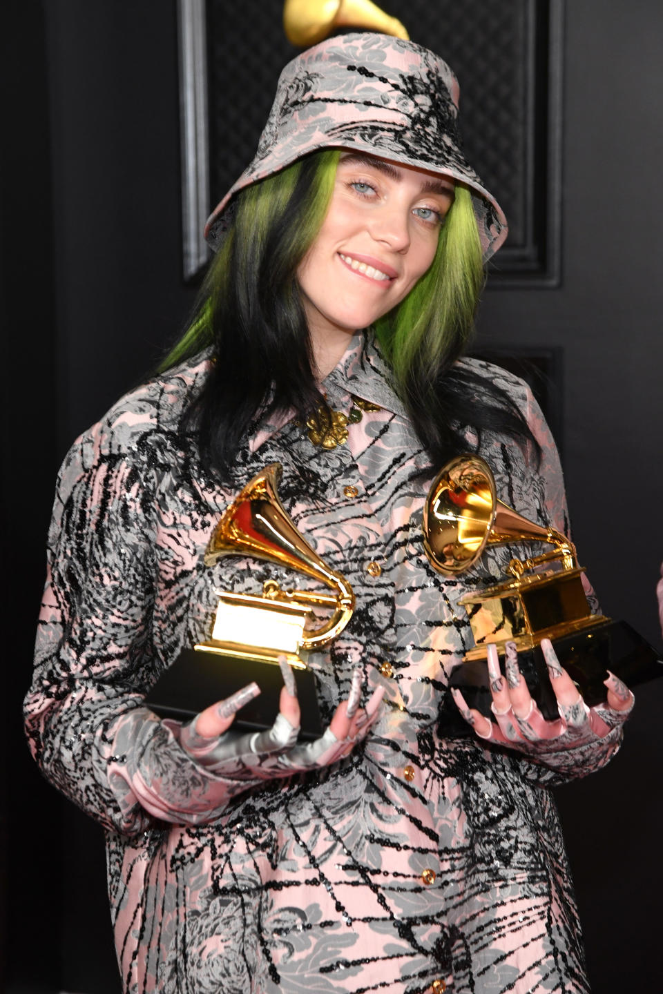 In a matching print outfit and hat, holding awards