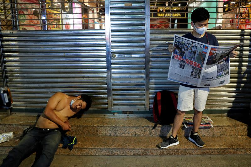 A supporter of Apple Daily newspaper, reads a copy of Apple Daily newspaper to support media mogul Jimmy Lai Chee-ying, founder of Apple Daily after he was arrested by the national security unit, in Hong Kong