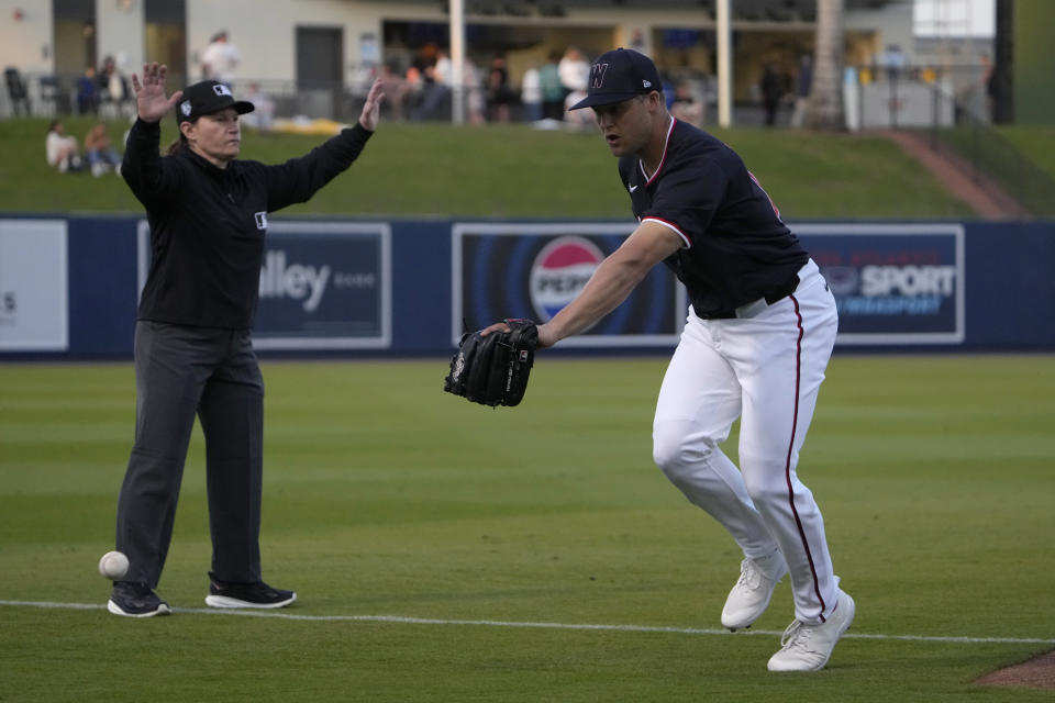Washington Nationals third baseman Nick Senzel, right, reaches for a foul ball as third base umpire Jen Pawol makes the call during the first inning of a spring training baseball game against the Houston Astros Saturday, Feb. 24, 2024, in West Palm Beach, Fla. (AP Photo/Jeff Roberson)