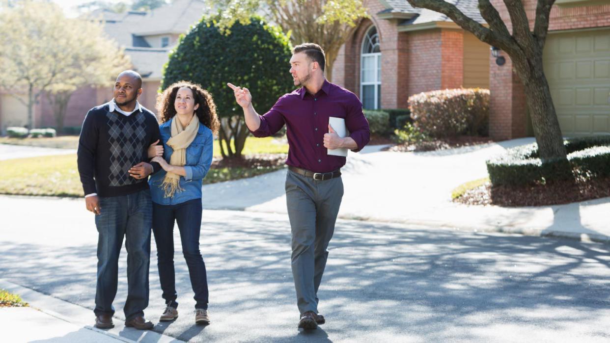 Couple walking on residential street with agent