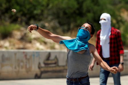 Palestinian boy hurls stones at Israeli forces during clashes at a protest against Bahrain's workshop for U.S. peace plan, near Hebron, in the Israeli-occupied West Bank