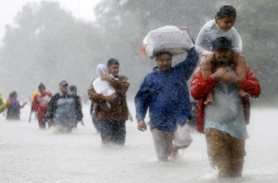 septyni suaugusieji braižo per atogrąžų audros telkinių potvynius, nešini vaikais ir krepšiais