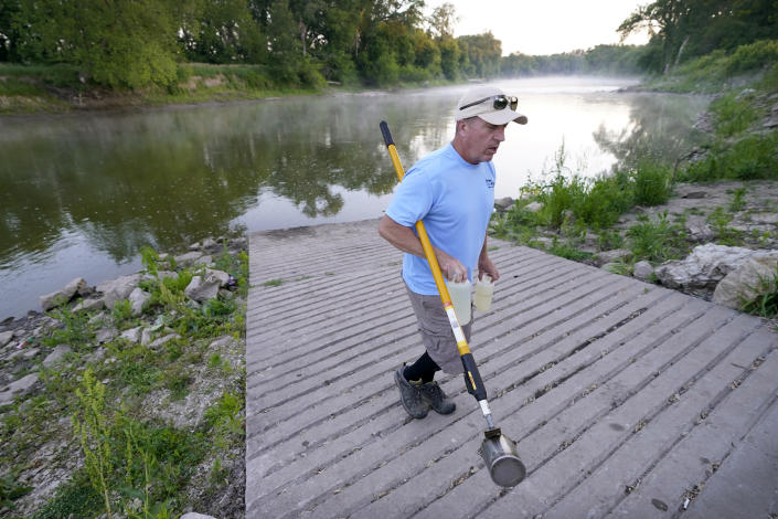 Des Moines Water Works employee Bill Blubaugh makes his way to his truck after collecting a water sample from the Raccoon River, Thursday, June 3, 2021, in Des Moines, Iowa. Each day the utility analyzes samples from the Raccoon River and others from the nearby Des Moines River as it works to deliver drinking water to more than 500,000 people in Iowa's capital city and its suburbs. (AP Photo/Charlie Neibergall)