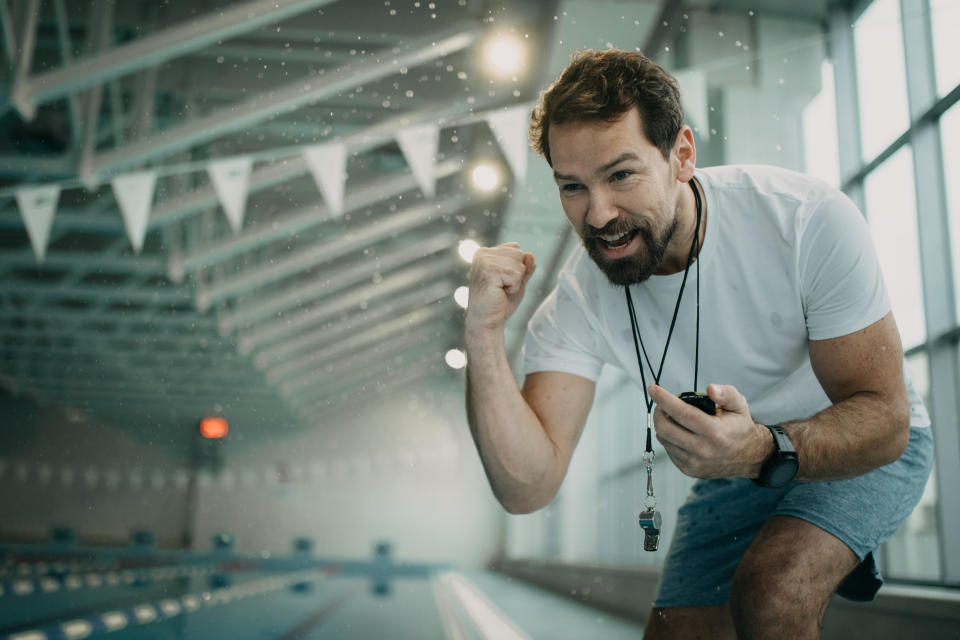 Adult man instructor or mentor with stopwatch encouraging swimmer during training