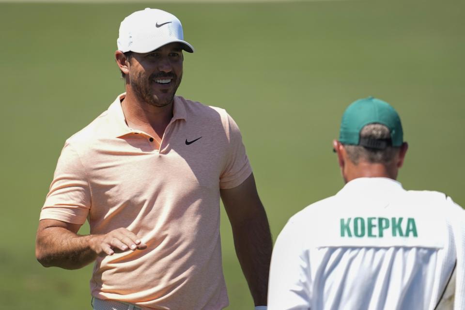 Brooks Koepka talks with his caddie on the driving range during a practice round in preparation for the Masters golf tournament at Augusta National Golf Club Monday, April 8, 2024, in Augusta, Ga. (AP Photo/George Walker IV)