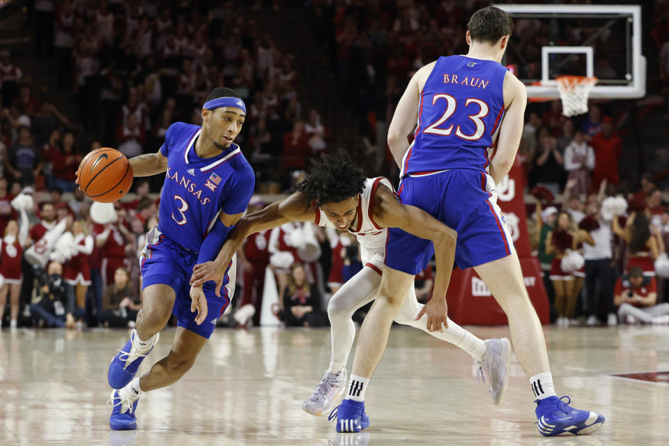 Kansas guard Dajuan Harris Jr. (3) drives the ball against Oklahoma guard Milos Uzan, center, who is blocked by Kansas forward Parker Braun (23), during the first half of an NCAA college basketball game Saturday, Feb. 17, 2024, in Norman, Okla. (AP Photo/Garett Fisbeck)