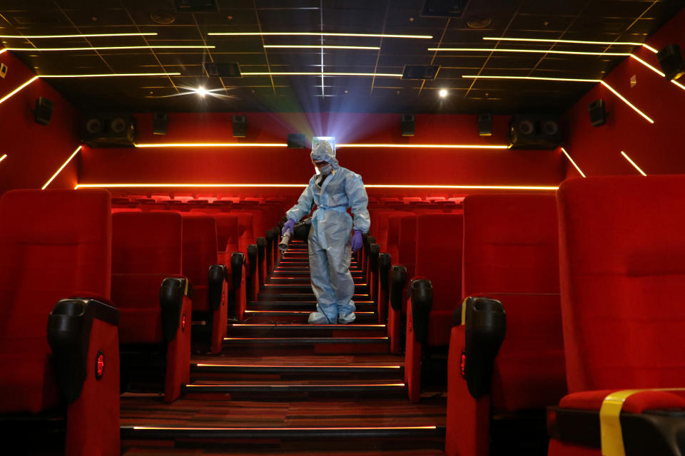 A worker wearing personal protective equipment (PPE) sanitizes seats inside the Inox Leisure movie theatre ahead of its reopening, amidst the outbreak of the coronavirus disease (COVID-19), in Mumbai, India, October 13, 2020. REUTERS/Niharika Kulkarni