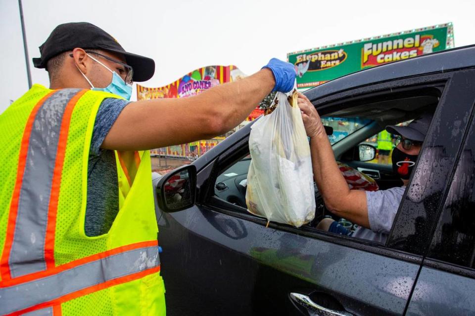 Food vendor employee Alejandro Pons, 18 delivers an order to the window of a driver during the Miami-Dade County Youth Fair food drive-through in Miami, Florida on Saturday, July 11, 2020.