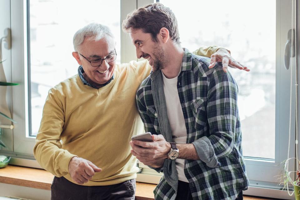 father and son laughing and using phone