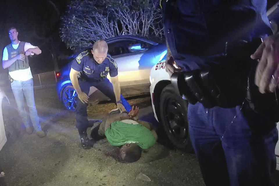 FILE - In this May 10, 2019 image from Louisiana State Trooper Lt. John Clary's body camera video, Trooper Kory York stands over Ronald Greene lying on his stomach outside of Monroe, La. The video shows Louisiana state troopers stunning, punching and dragging Greene as he apologizes for leading them on a high-speed chase. More than a year and a half after Louisiana state troopers were captured on body camera video brutalizing Greene during his fatal arrest, police brass were still trying to blame his death on a car crash at the end of a high-speed chase. (Louisiana State Police via AP)