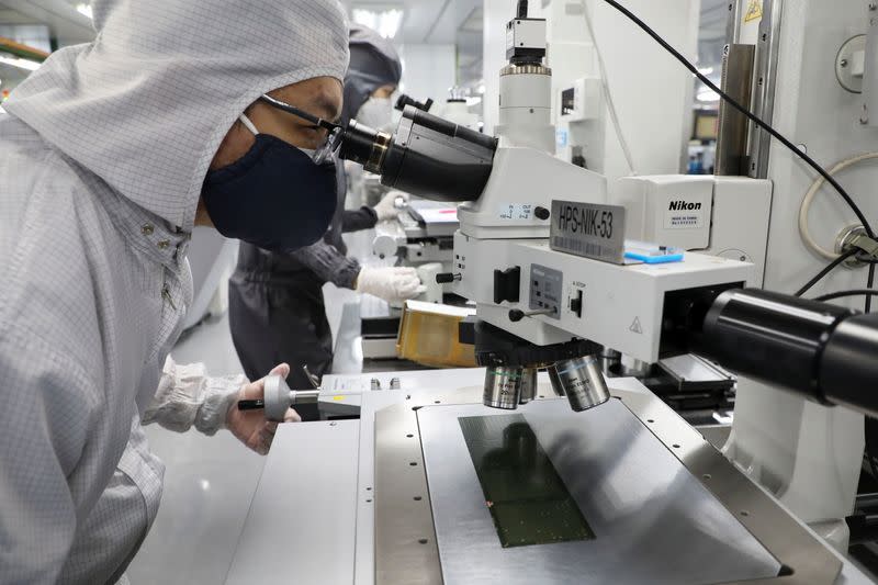 A worker inspects semiconductor chips at the chip packaging firm Unisem (M) Berhad plant in Ipoh