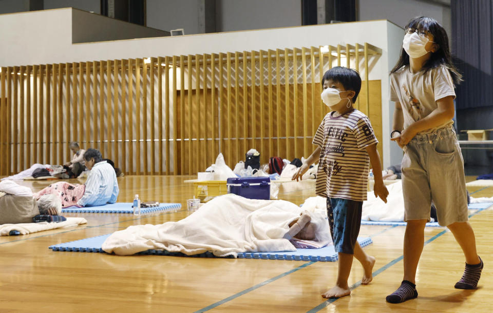 Children wearing face masks walk at a shelter after being evacuated, in Ashikita town, Kumamoto prefecture, southwestern Japan, Saturday, July 4, 2020. Heavy rain triggered flooding and mudslides on Saturday as more than 75,000 residents in the prefectures of Kumamoto and Kagoshima were asked to evacuate following pounding rains overnight. (Kyodo News via AP)