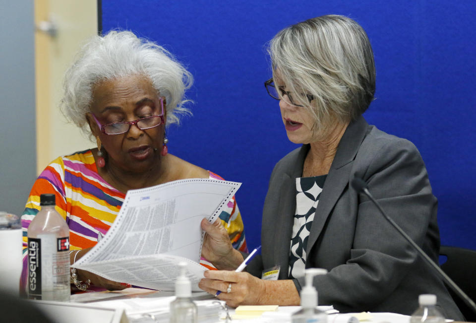 FILE- In this Nov. 9, 2018 file photo Brenda Snipes, left, Broward County Supervisor of Elections, looks at a ballot with Betsy Benson, canvasing board chair during a canvasing board meeting in Lauderhill, Fla. Snipes is a target for the GOP, including former Gov. Jeb Bush, who appointed her to the post in 2003. Snipes, a Democrat, has been re-elected since then, and is unapologetic about her record. (AP Photo/Joe Skipper, File)