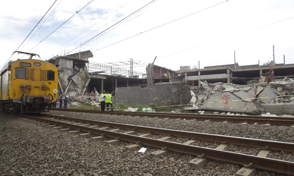 A commuter train moves past a building that collapsed in the South African town of Tongaat