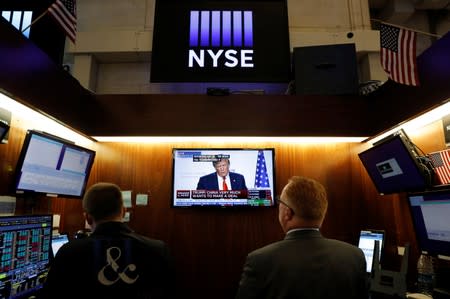 Traders watch monitors displaying a media conference with U.S. President Donald Trump live at the G7 summit on the trading floor at the New York Stock Exchange (NYSE) in New York City