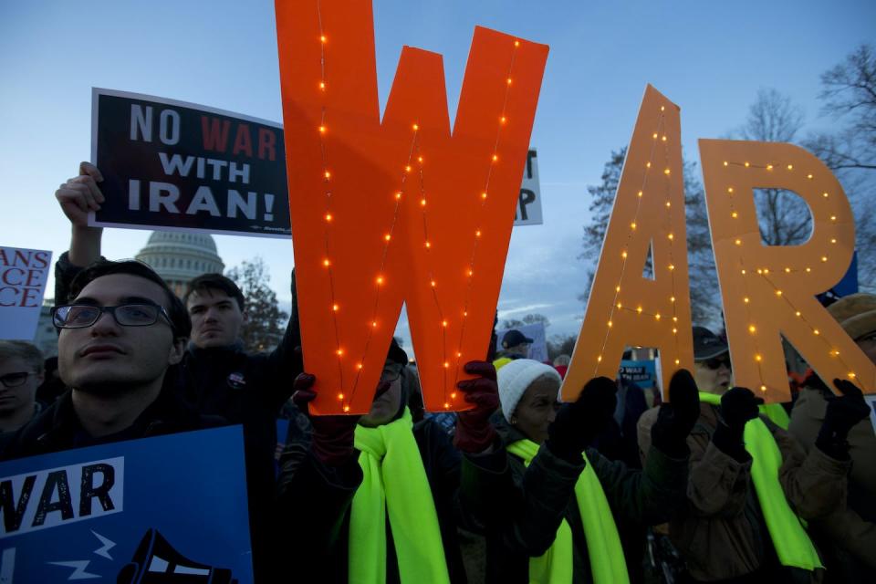 Demonstrators hold signs opposing war.