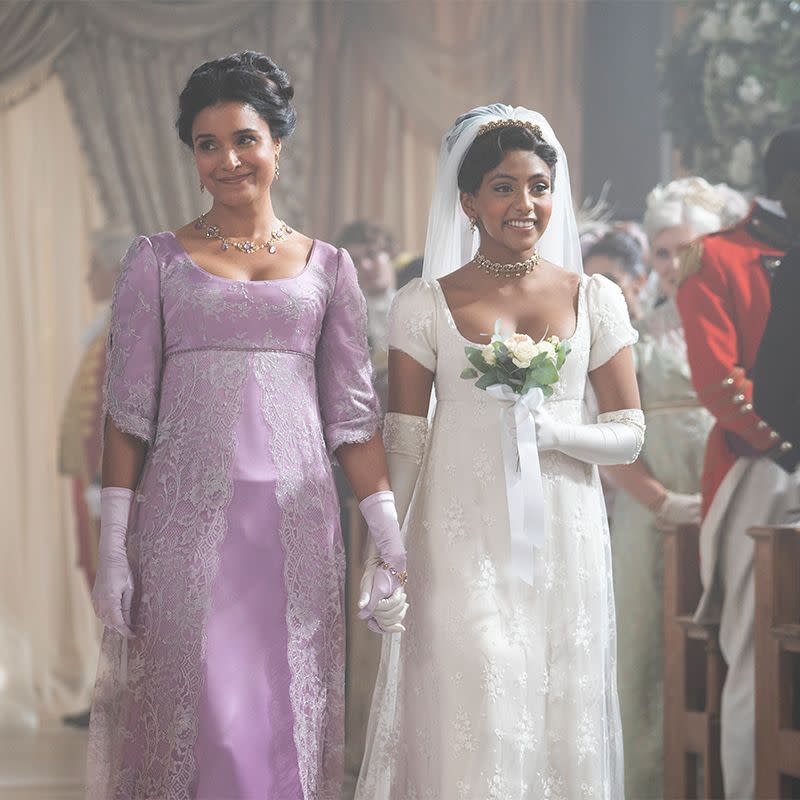 mary sharma in a purple dress walking edwina sharma down the aisle in her wedding dress