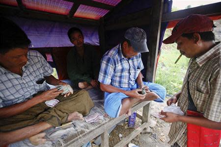 Tin Tun (R), a 38-year-old jade hand-picker, sells the jade which he found after searching the whole night at a jade mine in Hpakant township, Kachin State July 8, 2013. REUTERS/Minzayar