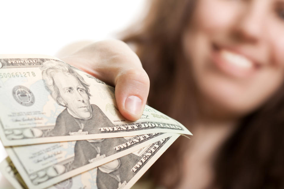 Smiling woman handing over $20 bills.