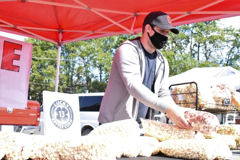 A vendor assists a customer at the Lucky Kettle Korn tent during the Lancaster Farmers Market on Saturday, May 15, 2021. Farmers markets in Lancaster, Millersport and Pickerington are good places to stop and shop during the summer.