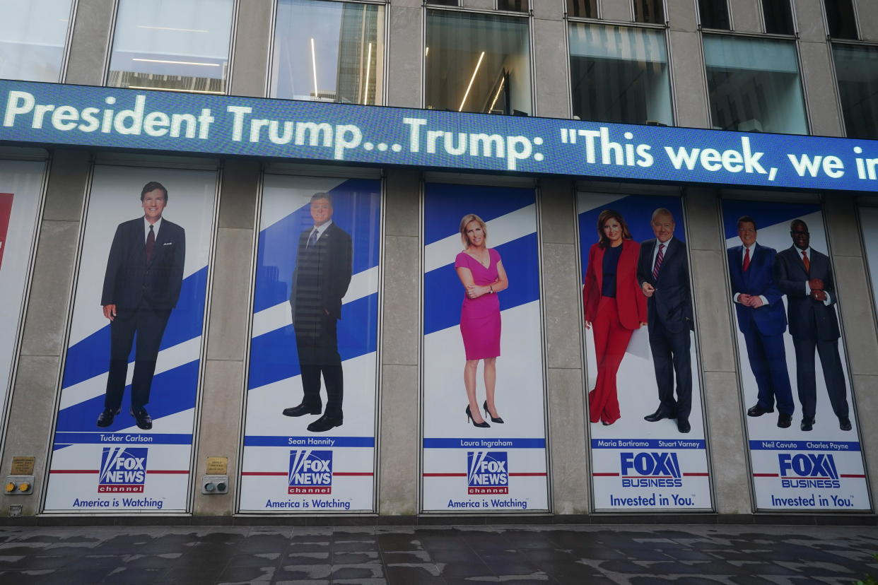 A series of posters on Fox News' headquarters show, from left, Carlson, Hannity, Ingraham above a slogan saying Fox News, America is Watching, and four presenters in its Business division, with a slogan reading: Fox Business, Invested in You.