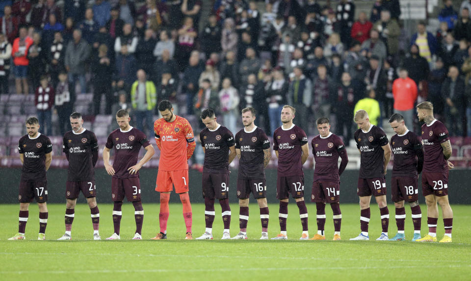 Hearts players stand wearing black armbands before the second half following the announcement of the death of Queen Elizabeth II, during the Europa Conference League Group A soccer match between Heart of Midlothian and Istanbul Basaksehir at Tynecastle Park, Edinburgh, Thursday, Sept. 8, 2022. (Robert Perry/PA via AP)