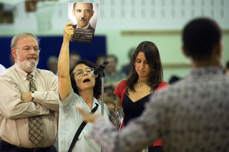 A woman holds up a picture of US President Barack Obama depicted as Nazi leader Adolf Hitler during a healthcare forum with US Congresswoman Donna Edwards (R), D-MD, in Germantown, MD, August 25, 2009.