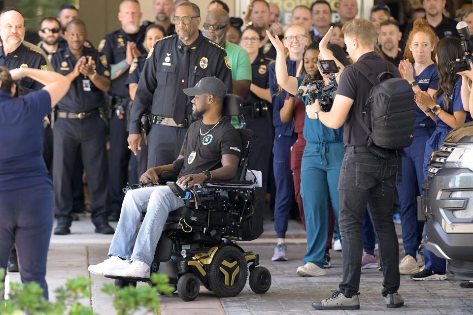 Wounded Officer Malik Daricaud of the Jacksonville Sheriff's Office makes a triumphant exit from Brooks Rehabilitation passing by lines of law enforcement and health care workers on Thursday. He was discharged from the hospital after a year and a month recovering from severe injuries from being shot by a man wanted for questioning who would later kill himself.